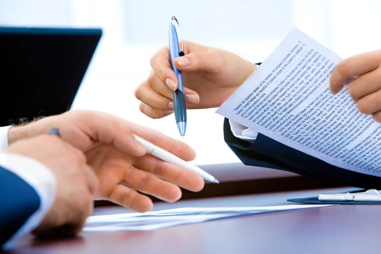 Person reviews car loan papers and a calculator at a kitchen table for an upside-down trade-in calculator.